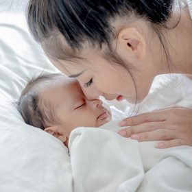 baby sleeps asian mother and touches her child with tenderness and cherishness.
